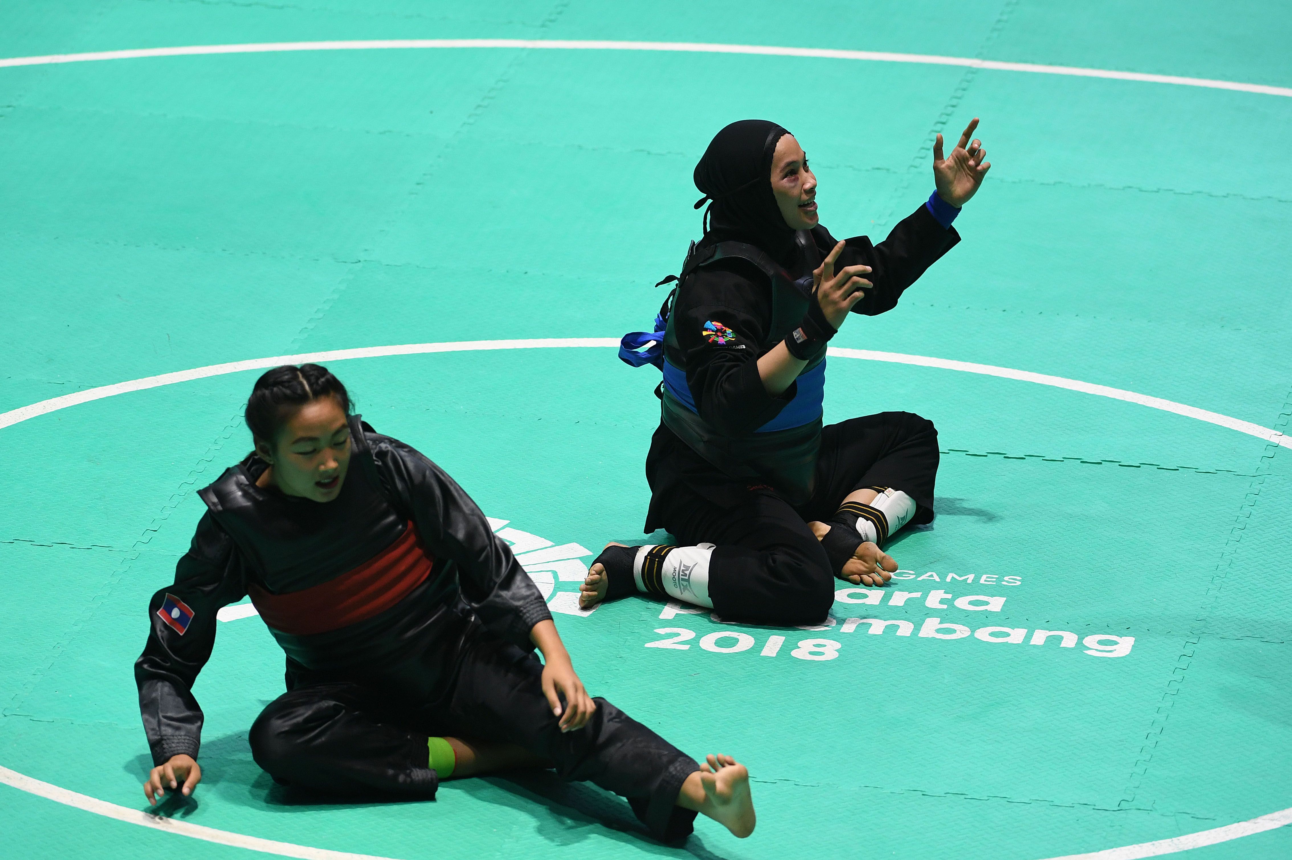 Ekspresi pesilat Indonesia Sarah Tria Monita (kanan) usai mengalahkan pesilat Laos Nong Oy Vongphakdy (kiri) dalam babak final Kelas C Putri Asian Games 2018 di Padepokan Pencak Silat Taman Mini Indonesia Indah (TMII), Jakarta, Senin (27/8). ANTARA FOTO/INASGOC/Melvinas Priananda/nak/18.