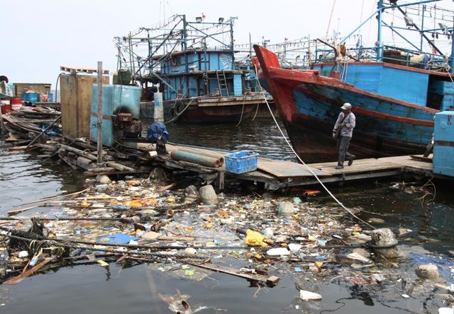 SAMPAH PLASTIK. Warga melintas di samping kapal yang bersandar di laut yang tercemar oleh sampah plastik, di Muara Angke, Penjaringan, Jakarta Utara, Rabu (28/11). Berdasarkan data Badan Pusat Statik, Indonesia menghasilkan 64 juta ton sampah plastik per tahun dengan 32 juta ton, di antaranya mengalir ke laut dan hal tersebut dikategorikan darurat sampah plastik sehingga perlu penanganan serius. ANTARA/RENO ESNIR
