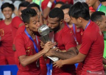 Pemain Timnas U-22 Sani Riski Fauzi (kiri) bersama Marinus Wanewar (tengah) mencium Piala AFF U-22 seusai penganugerahan piala di Stadion Nasional Olimpiade Phnom Penh, Kamboja, Selasa (26/2/2019). (Foto:Antara)