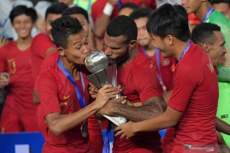 Pemain Timnas U-22 Sani Riski Fauzi (kiri) bersama Marinus Wanewar (tengah) mencium Piala AFF U-22 seusai penganugerahan piala di Stadion Nasional Olimpiade Phnom Penh, Kamboja, Selasa (26/2/2019). (Foto:Antara)
