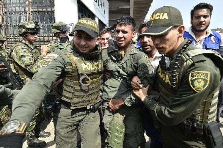 Colombian policemen accompany a Venezuelan police officer who deserted from Venezuela at the Simon Bolivar international bridge, in Cucuta, Colombia after President Nicolas Maduro's government ordered to temporary close down the border with Colombia on February 23, 2019. - Venezuela braced for a showdown between the military and regime opponents at the Colombian border on Saturday, when self-declared acting president Juan Guaido has vowed humanitarian aid would enter his country despite a blockade. (Photo by Luis ROBAYO / AFP)