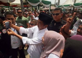 KAMPANYE TERBUKA JOKOWI DI ACEH. Calon presiden petahana nomor urut 01 Joko Widodo (kanan) berfoto dengan massa pendukung saat kampanye terbuka di Lhokseumawe, Aceh, Selasa (26/3). Dalam kampanye yang dihadiri ribuan pendukung, parpol pengusung, dan para ulama, Jokowi menyatakan optimistis bersama masyarakat Aceh bisa memenangkan suara pada Pemilihan Presiden 17 April mendatang. ANTARA FOTO/RAHMAD