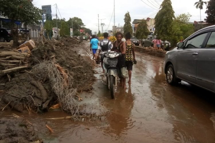 Warga mendorong motor melintasi sisa lumpur akibat banjir bandang di Sentani, Kabupaten Jayapura, Papua, Minggu, 17 Maret 2019. ANTARA/Gusti Tanati