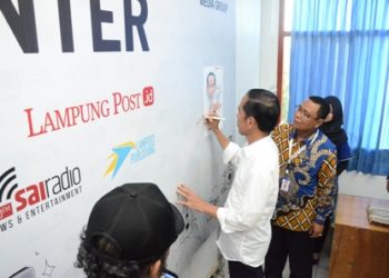 SEMBOYAN ANTIHOAKS. Presiden Joko Widodo menandatangani banner semboyan antihoaks milik surat kabar harian umum Lampung Post di ruang redaksi lantai 2 didampingi Pemimpin Redaksi Lampung Post Iskandar Zulkarnain, Jumat (8/3). (LAMPUNG POST/HENDRIVAN GUMALA)