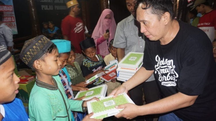 SERAHKAN BANTUAN. Salah satu sukarelawan Kombi Lampung menyerahkan bantuan Alquran kepada santri TPA, di Desa Pahawang, Margapunduh, Pesawaran, Sabtu (18/5). (DOKUMENTASI KOMBI LAMPUNG)