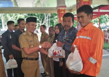 BAGIKAN SEMBAKO. Bupati Lampung Barat Parosil Mabsus secara simbolis menyerahkan paket sembako kepada pegawai golongan rendah dan THLS serta masyarakat tidak mampu di halaman kantor bupati, Selasa (21/5). (LAMPUNG POST/ELIYAH)