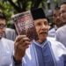 Ketua Dewan Kehormatan Partai Amanat Nasional (PAN) Amien Rais (tengah) menunjukkan buku berjudul Jokowi People Power saat jeda pemeriksaan untuk Shalat Jumat di Direktorat Reserse Kriminal Umum (Ditreskrimum) Polda Metro Jaya, Jakarta, Jumat (24/5/2019). Amien Rais diperiksa sebagai saksi atas kasus dugaan makar dengan tersangka Eggi Sudjana. ANTARA FOTO/Aprillio Akbar/foc.
