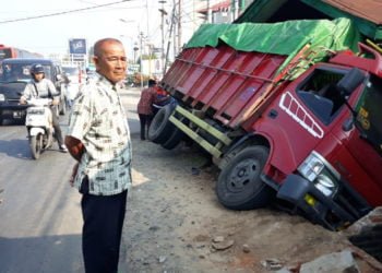 SERUDUK KIOS. Dump truck bermuatan kopi yang menabrak kios dan seorang warga di Jalan Ahmad Yani, Gedongtataan, Pesawaran, Jumat (21/6). Kecelakaan tersebut mengakibatkan satu orang mengalami luka parah. (LAMPUNG POST/AHMAD AMRI)