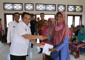 SERAHKAN KARTU. Wakil Bupati Way Kanan Edward Antony saat menyerahkan Kartu Keluarga Sejahtera (KKS) dan Bantuan Pangan Nontunai (BPNT) kepada masyarakat Kecamatan Bumiagung di aula kecamatan setempat, Rabu (26/6). (LAMPUNG POST/CANDRA PUTRA WIJAYA)