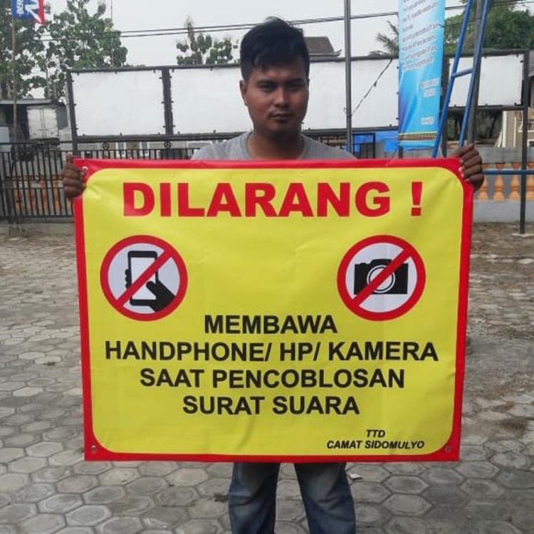 LARANGAN. Pemberitahuan larangan membawa HP dipasang di setiap tempat pencoblosan. (DOKUMENTASI KECAMATAN SIDOMULYO)