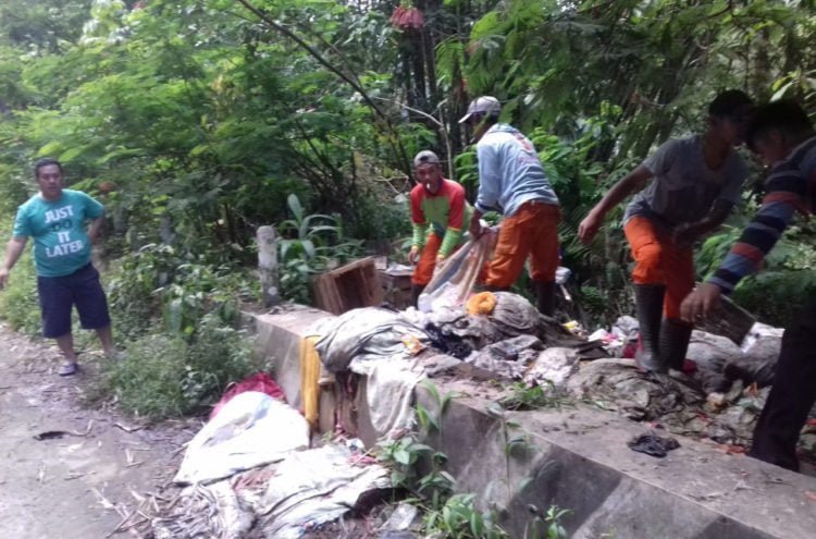 BERSIHKAN SAMPAH. Petugas kebersihan Dinas Lingkungan Hidup Lampung Barat membersihkan tumpukan sampah yang dibuang masyarakat secara sembarangan di jalan perlintasn. Dinas LH mengerahkan sejumlah armada dan personal. (DOKUMENTASI DLH LAMBAR)