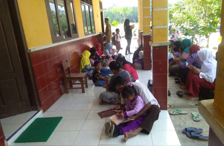 AJAK ORANG TUA. Peringati Hari Anak Nasional 2019, penggiat literasi Motor Pustaka Lampung Selatan mengajak orang tua membaca buku untuk anaknya. Sejumlah ibu dan anak bersama-sama membaca buku di SDN 1 dan TK PGRI Desa Pasuruan, Kecamatan Penengahan, Selasa (23/7).  (LAMPUNG POST/AAN KRIDOLAKSONO)