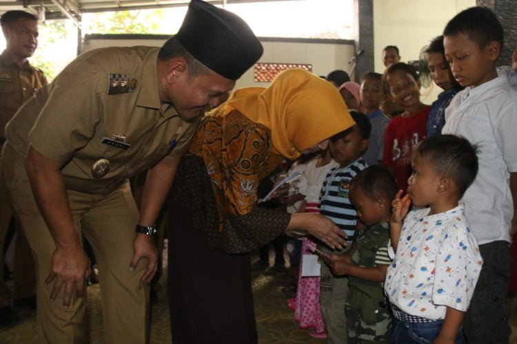 BERIKAN BANTUAN. Wakil Bupati Pringsewu Fauzi, didampingi istri memberikan bantuan kepada anak-anak penderita talasemia dalam kegiatan silaturahmi dan halalbihalal jajaran pengurus KONI Kabupaten Pringsewu dan Yayasan Jantung Indonesia di rumah Wakil Bupati Pringsewu Fauzi di Pringsewu Barat, Senin (1/7). (DOKUMENTASI HUMAS PEMKAB PRINGSEWU)