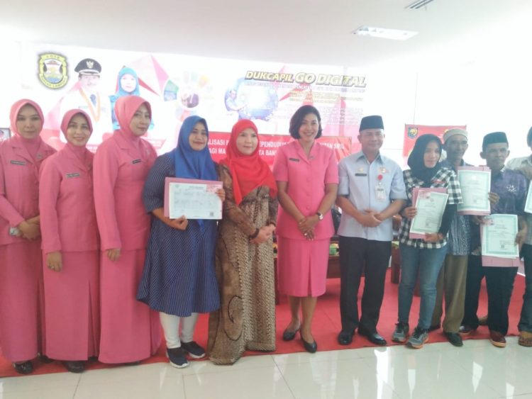 PEMBAGIAN AKTE. Ketua TP-PKK Bandar Lampung Eva Dwiana Herman HN dan Ketua Bhayangkari Lampung Sarie Purwadi Arianto bersama warga penerima akte kelahiran dan KIA di gedung Mal Pelayanan Pemkot setempat, Rabu (21/8).  (LAMPUNG POST/DETA CITRAWAN)