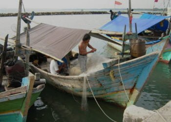 TIDAK MELAUT. Nelayan di PPI Bom Kalianda tidak melaut sejak beberapa hari ini lantaran tangkapan minim akibat angin dan gelombang besar di perairan selatan Selat Sunda. Nelayan memperbaiki jaring di atas kapal, Jumat (9/8). (LAMPUNG POST/AAN KRIDOLAKSONO)