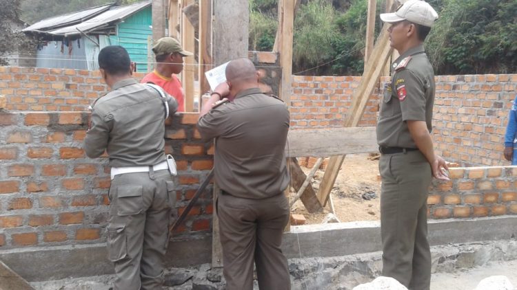 DITEGUR. Petugas dari Tim Satpol PP Lampung Barat saat meminta pemilik bangunan yang melanggar perda untuk membuat pernyataan, Rabu (18/9). Pembangunan empat rumah dianggap melanggar Perda tentang Bangunan Gedung. (DOKUMENTASI SAT POL LAMBAR)