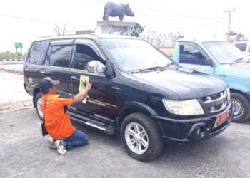 PASANG STIKER. Petugas memasang stiker logo Pemkab Lamtim pada mobil dinas, Selasa (24/9). Pemasangan stiker tersebut agar kendaraan dinas itu tidak disalahgunakan. (LAMPUNG POST/DJONI HARTAWAN JAYA)