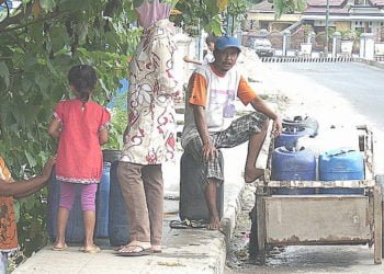 CARI AIR. Warga Dusun Pandegolan, Desa Hatta,  Kecamatan Ketapang, Lampung Selatan, memanfaatkan air dari sumber mata air yang masih mengalir di ruas Jalan Lintas Sumatera desa setempat, Senin (30/9). Kekeringan membuat warga mengalami krisis air bersih. (LAMPUNG POST/AAN KRIDOLAKSONO)