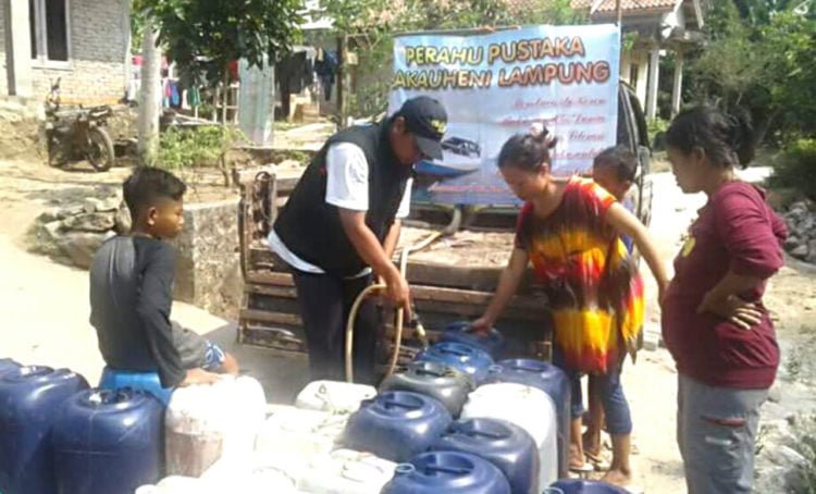BAGIKAN AIR BERSIH. Sukarelawan Perahu Pustaka saat menyalurkan bantuan air bersih ke Dusun Kayutabu dan Pematangmacan, Desa Klawi, Kecamatan Bakauheni, Lampung Selatan, yang dilanda kekeringan beberapa waktu lalu. Sayang, kini mereka hanya menyediakan air bersih gratis dan kendaraan saja. (LAMPUNG POST/AAN KRIDOLAKSONO)