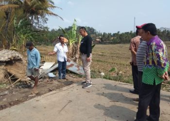 TINJAU LOKASI. Wakil Bupati Pringsewu Fauzi (kaus hitam) meninjau rumah roboh dan memberikan bantuan kepada warga yang terkena musibah, Jumat (18/10). LAMPUNG POST/WIDODO