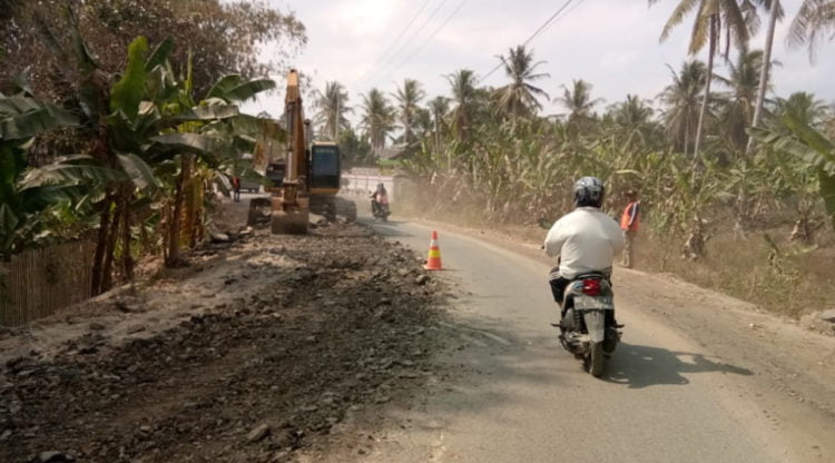 BERDEBU. Seorang pengendara sepeda motor saat melintasi proyek perbaikan jalan poros Kecamatan Palas, Lampung Selatan, Selasa (1/10). Debu yang ditimbulkan dari perbaikan jalan tersebut dikeluhkan warga setempat. (LAMPUNG POST/ARMANSYAH)
