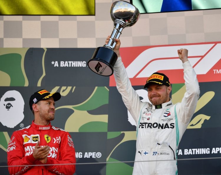 ANGKAT TROFI. Pembalap Mercedes, Valtteri Bottas (kanan) mengangkat trofi untuk merayakan kemenangannya di samping pembalap Ferrari yang berada di tempat kedua, Sebastian Vettel di podium setelah Grand Prix Jepang Formula Satu di Suzuka, Minggu (13/10).(AFP/TOSHIFUMI KITAMURA)