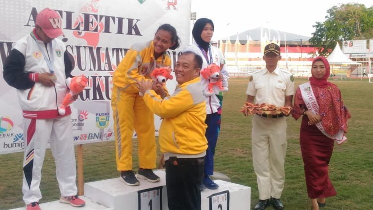 SABET EMAS. Nabella Ariantika saat menerima pengalungan emas dari Kadispora Lampung Hannibal usai menjadi yang terbaik cabang atletik nomor sapta lomba di Stadion Semarak Bengkulu, Selasa (5/10). (DOKUMENTASI HUMAS KONI LAMPUNG)