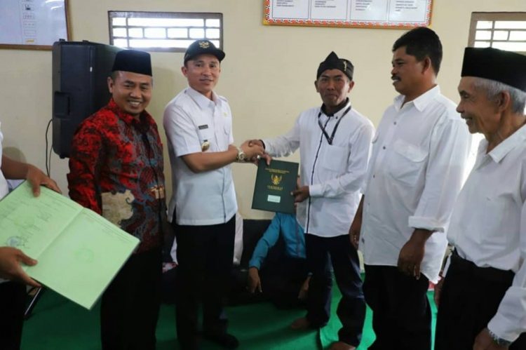 BAGIKAN SERTIFIKAT. Bupati Lampung Barat Parosil Mabsus membagikan sertifikat tanah program PTSL kepada masyarakat. DOK PEMKAB LAMPUNG BARAT