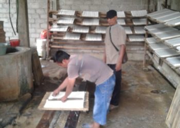 PERAJIN TAHU. Kepala Desa (Kades) Kemaloabung, Kecamatan Abung Selatan, Lampung Utara, Supriono, mendampingi Abdul Rohman Hakim, perajin tahu, saat memotong produk olahannya di sentra produksi miliknya di desa setempat, Kamis (31/10). LAMPUNG POST/YUDHI HARDIYANTO