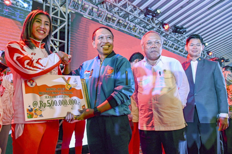 SERAHKAN BONUS. Menteri Pemuda dan Olahraga Zainudin Amali (kedua kiri) didampingi Menteri PUPR yang juga Ketua Umum Pengurus Besar Persatuan Dayung Seluruh Indonesia (PB PODSI) Basuki Hadimuljono (kedua kanan) dan Ketua NOC Raja Sapta Oktohari (kanan) memberikan bonus kepada atlet atletik Emilia Nova (kiri) pada penyerahan bonus atlet peraih medali SEA Games 2019 Filipina di Jakarta, Kamis (12/12). Peraih emas kategori perorangan mendapatkan bonus Rp500 juta, ganda Rp400 juta, dan beregu Rp350 juta. (ANTARA/MUHAMMAD ADIMAJA)
