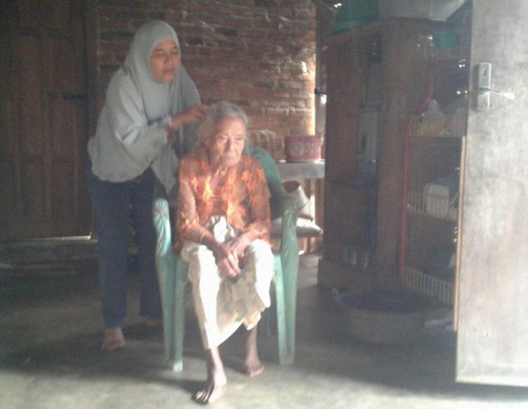 SISIR RAMBUT. Pembina Bina Keluarga Lansia (BKL) Gesang, Desa Kemaloabung, Kecamatan Abung Selatan, Lampung Utara, Nusriyah, menyisir rambut Surkiyah (84), saat kunjungan lansia, Jumat (20/12). n LAMPUNG POST/YUDHI HARDIYANTO