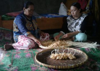 KLANTING GETHUK. Nur Aini bersama putrinya menguntai klanting gethuk buatannya dengan tali bambu sebelum dipasarkan di kediamannya, Rabu (4/12). LAMPUNG POST/YUDHI HARDIYANTO