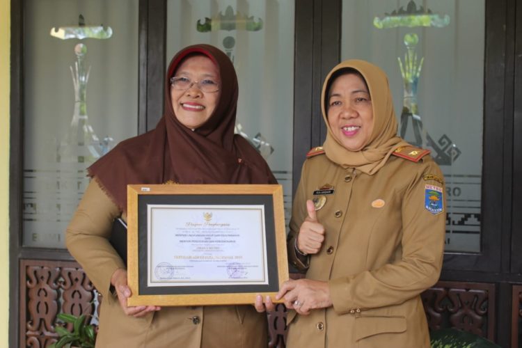 TUNJUKKAN PIAGAM. Kepala Dinas Pendidikan Kota Metro, Ria Andari dan Kepala SMAN 1 Metro, Purwaningsih foto bersama menunjukkan piagam penghargaan Adiwiyata Nasional yang diraih SMAN 1 Kota Metro dan dikeluarkan Kementerian Lingkungan Hidup dan Kehutanan (KLHK). LAMPUNG POST/SUPRAYOGI