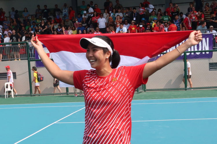 EMAS TUNGGAL PUTRI: Petenis tunggal putri Indonesia Aldila Sutjiadi membawa bendera Merah Putih setelah menang 6-0 dan 7-5 atas petenis Vietnam Savanna Ly Nguyen pada final tenis tunggal putri SEA Games 2019 di lapangan Rizal Memorial Tennis Centre, Manila, Filipina, Jumat (6/12). (ANTARA/MICHAEL SIAHAAN)