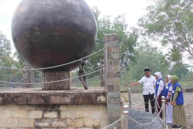 BENDA BERSEJARAH. Kepala Museum Ketransmigrasian Bapak Suhardi menjelaskan mengenai bola besi yang dulu digunakan untuk membuka lahan di daerah transmigrasi, Rabu (4/12), di Museum Ketransmigrasian, Gedongtataan, Pesawaran. LAMPUNG POST/SUKISNO