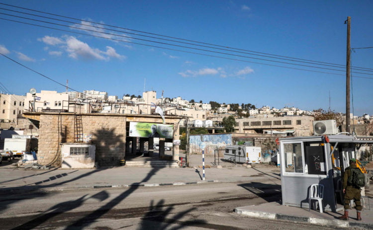 POS PEMERIKSAAN. Seorang tentara Israel berdiri di dekat pos pemeriksaan di seberang sebuah bangunan pasar lama di sepanjang Jalan al-Shuhada, Hebron di Tepi Barat yang diduduki pada 1 Desember 2019. (HAZEM BADER/AFP)