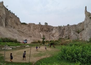 GUNUNG KUNYIT. Anak-anak bermain sepak bola di lapangan tepat di bawah Gunung Kunyit, Kecamatan Bumiwaras, Bandar Lampung, Selasa (3/12). Warga sekitar tidak merasa khawatir walau sering terjadi longsoran.(LAMPUNG POST/SUKISNO)