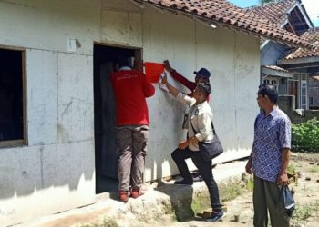 PASANG STIKER. Tim pendamping PKH memasang stiker penerima PKH pertama di Desa Kemukus, Kecamatan Ketapang, Lampung Selatan, Selasa(14/1). LAMPUNG POST/AAN KRIDOLAKSONO