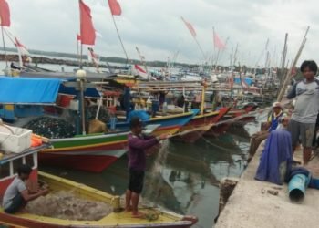 PERBAIKI JARING. Beberapa nelayan di Dermaga Bom Kalianda, Lampung Selatan, memperbaiki jaring saat tidak melaut, Kamis (9/1). LAMPUNG POST/ARMANSYAH