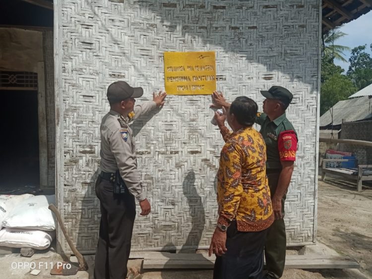 TANDA KHUSUS RUMAH. Kepala Desa Lebungnala, Kecamatan Ketapang, Lamsel Ajun Wiyono (tengah) didampingi bhabinkamtibmas dan nabinsa saat melihat pemasangan tanda khusus di rumah keluarga penerima manfaat (KPM) bantuan Program Keliarga Harapan (PKH) di Desa Lebungnala, Jumat (17/1). LAMPUNG POST/AAN KRIDOLAKSONO