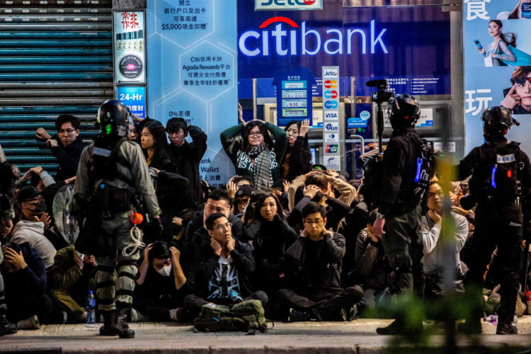 DITAHAN. Polisi menahan sekelompok orang setelah pawai prodemokrasi di Hong Kong pada 1 Januari 2020. (ISAAC LAWRENCE/AFP)