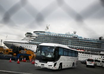 KEMATIAN RENDAH. Sebuah bus dengan sopir yang mengenakan alat pelindung meninggalkan dermaga Pelabuhan Yokohama, Jepang, Jumat (14/2), di sebelah kapal pesiar Diamond Princess yang mengarantina 3.600 orang karena kekhawatiran akan virus corona COVID-19. Kematian akibat virus corona COVID-19 masih rendah dibandingkan SARS dan MERS. (CHARLY TRIBALLEAU/AFP)