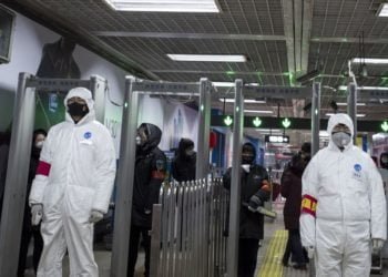 Petugas yang mengenakan pakaian pelindung bersiaga di stasiun kereta api di Beijing, 26 Januari 2020. (Foto: AFP/NOEL CELIS)
