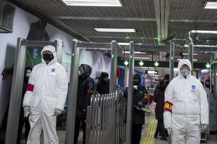 Petugas yang mengenakan pakaian pelindung bersiaga di stasiun kereta api di Beijing, 26 Januari 2020. (Foto: AFP/NOEL CELIS)