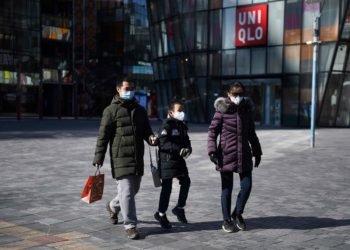 Warga mengenakan masker saat berjalan di depan pusat perbelanjaan yang nyaris kosong di Beijing, Tiongkok, 16 Februari 2020. (Foto: AFP/GREG BAKER)