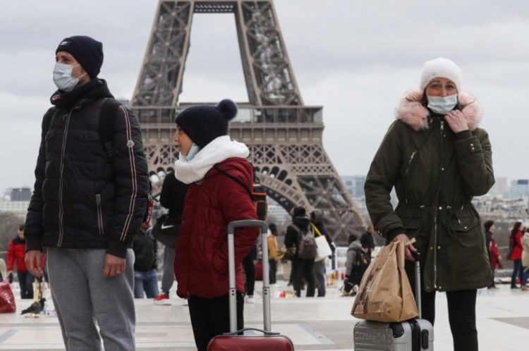 Warga dan turis mengenakan masker dalam mengantisipasi virus korona covid-19 di depan Menara Eiffel, Paris, Prancis, 12 Maret 2020. (Foto: Ludovic Marin/AFP via Getty Images)