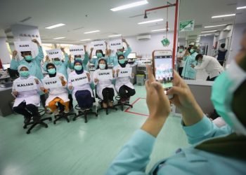 Petugas medis melakukan foto dengan memegang tulisan "Kami Tetap Bekerja Untuk Kalian, Kalian Tetap di Rumah Untuk Kami" di RSCM, Jakarta. MI/Ramdani