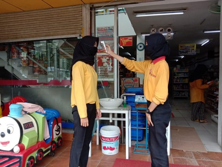 MASA PEMULIHAN COVID-19. Pegawai salah satu Superstore Chandra melakukan protokol kesehatan dengan memeriksa suhu tubuh pengunjung saat akan memasuki Superstore Chandra Way Kandis, Bandar Lampung, beberapa waktu yang lalu. LAMPUNG POST/ZAINUDDIN