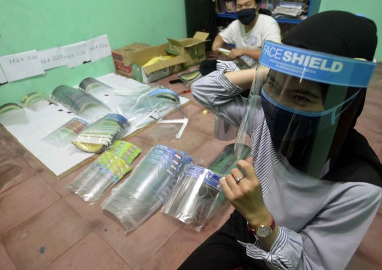 Mahasiswa yang tergabung dalam Komunitas Insan Cekatan (KIC) mencoba pelindung wajah yang dibutuhkan pada pandemic COVID-19 yang banyak di butuhkan untuk pencegahan penularan akibat virus Corona di sebuah industri rumahan di Bandar Lampung, Lampung, Rabu (3/6). Komunitas gabungan mahasiswa ini dalam sehari memproduksi 300 buah pelindung wajah dengan harga antara Rp10.000 sampai Rp.20.000 per buah, selain untuk dijual, komunitas ini juga memberikan bantuan pelindung wajahnya produksinya kepada petugas medis di rumah sakit yang membutuhkan. ANTARA FOTO/Ardiansyah.