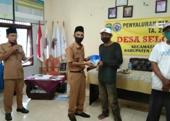 SERAHKAN BLT. Kepala Desa Seloretno, Kecamatan Sidomulyo, Lampung Selatan, Achmad Subari, menyerahkan pencairan BLT DD, di balai desa setempat, Selasa (16/6). LAMPUNG POST/PERDHANA WIBYSONO